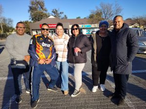 A group of travellers smiling together in a sunny parking area