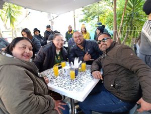 A group of travellers smiling and enjoying drinks together at an outdoor café during a DBD Travel guided group tour.